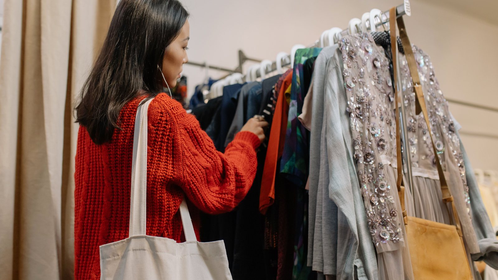A shopper browsing garments on a clothing rack in a fashion store